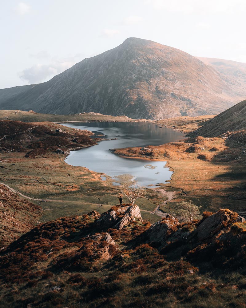 A man standing in nature overlooks a distant hill