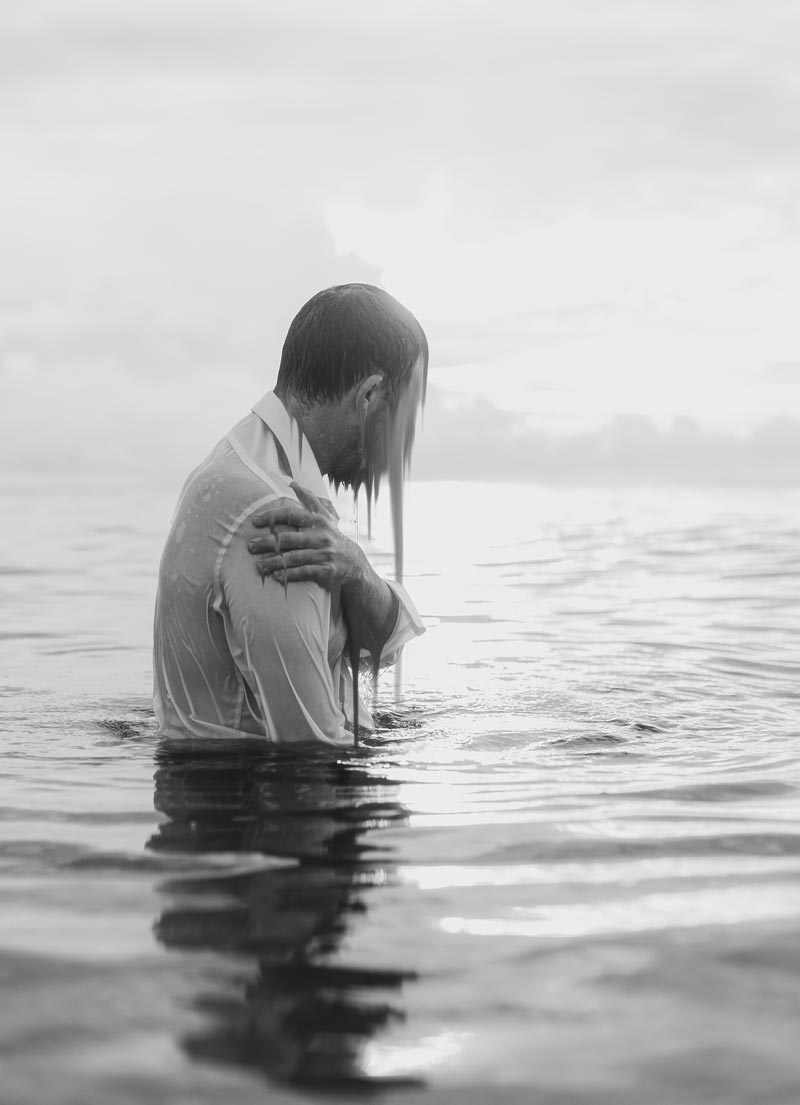 A man stands in waist high water with his face blurred