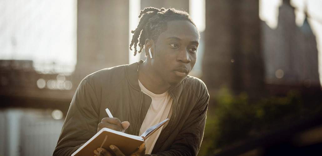 man writing in notebook outdoors