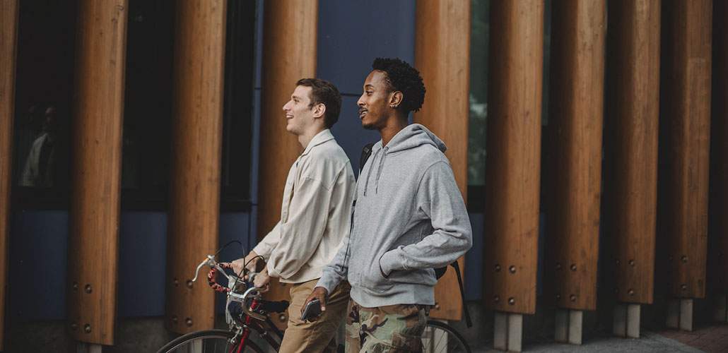 Two men walking, one with a bike